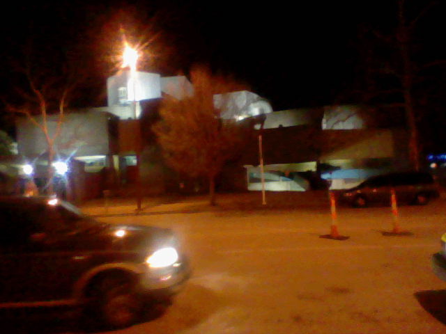 a night s of parking spaces in front of an apartment building with the lights on