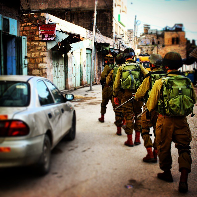 men are walking on a street while other men are behind them