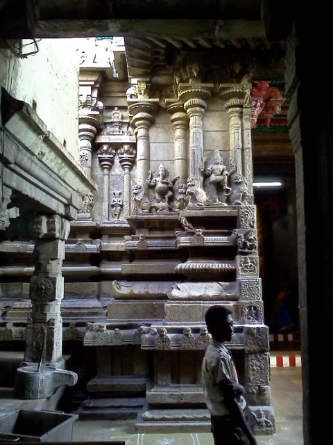 boy standing on stone step next to intricately carved columns
