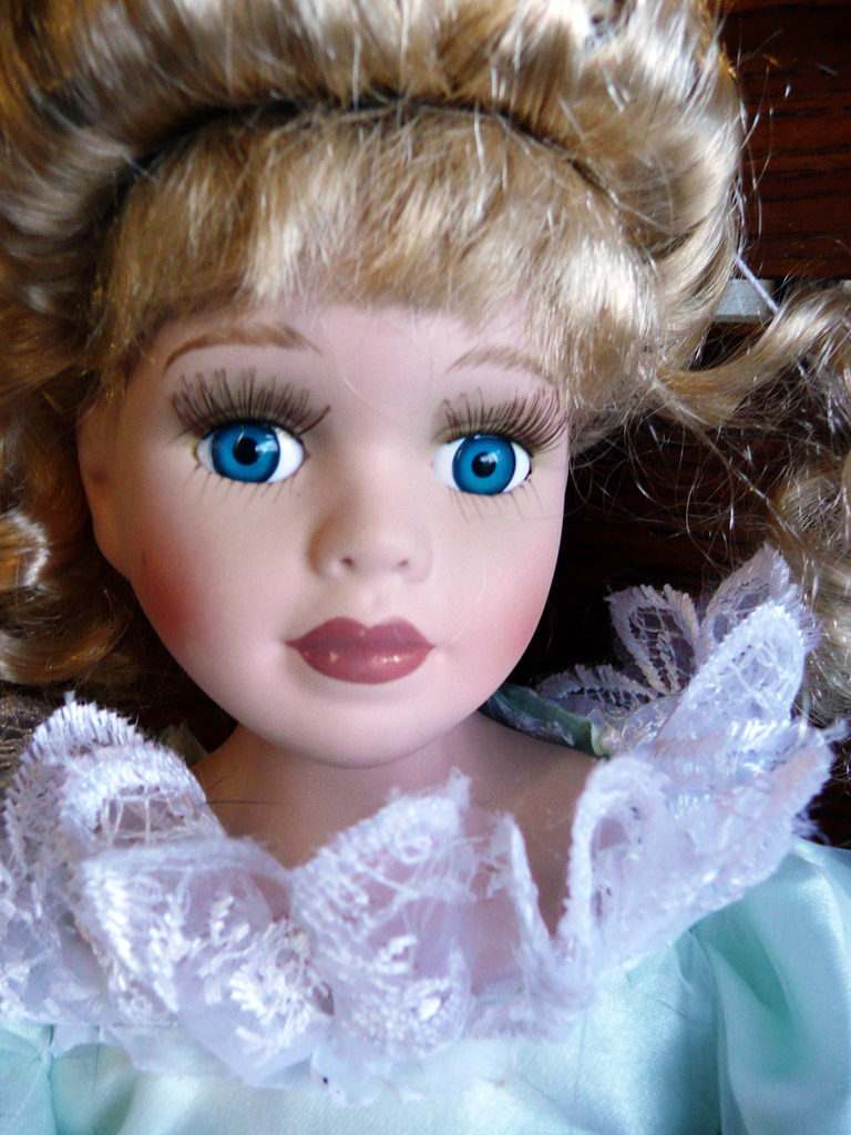 a doll with blue eyes wearing white dress and bonnet