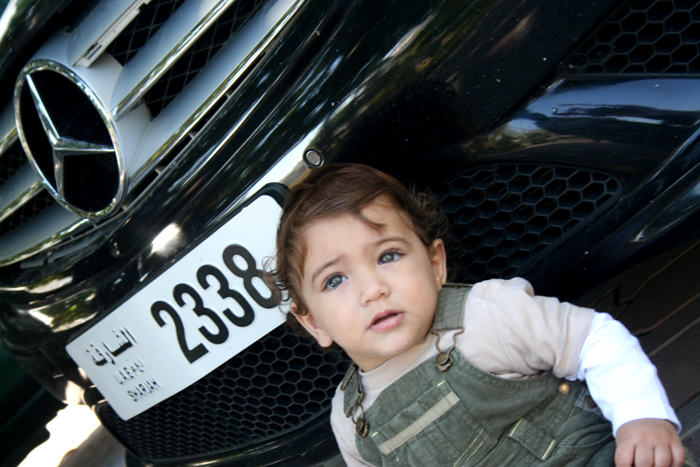 a small child is standing under the front grille of a car