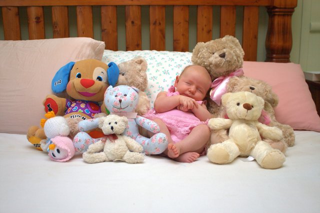 an infant laying in between many stuffed animals