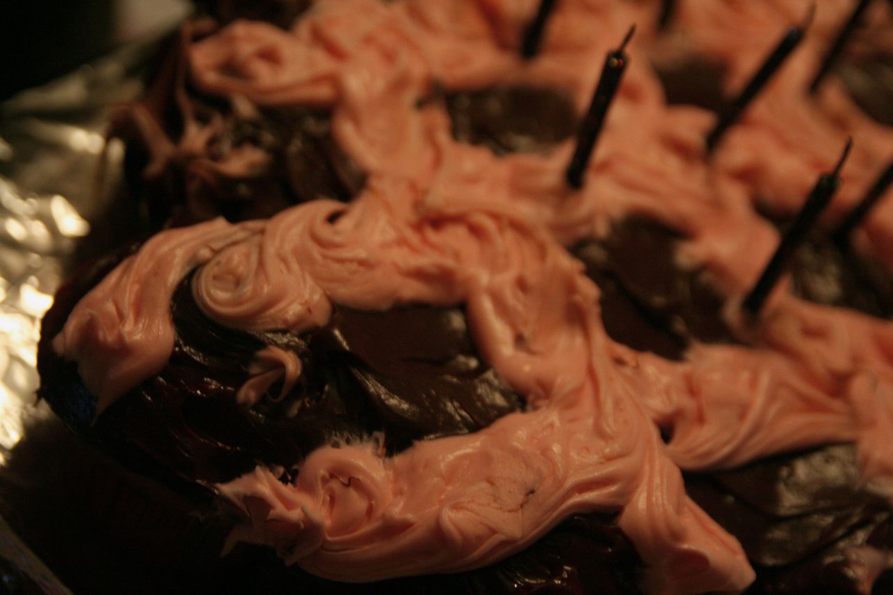 a chocolate cupcake with pink icing and chocolate sticks