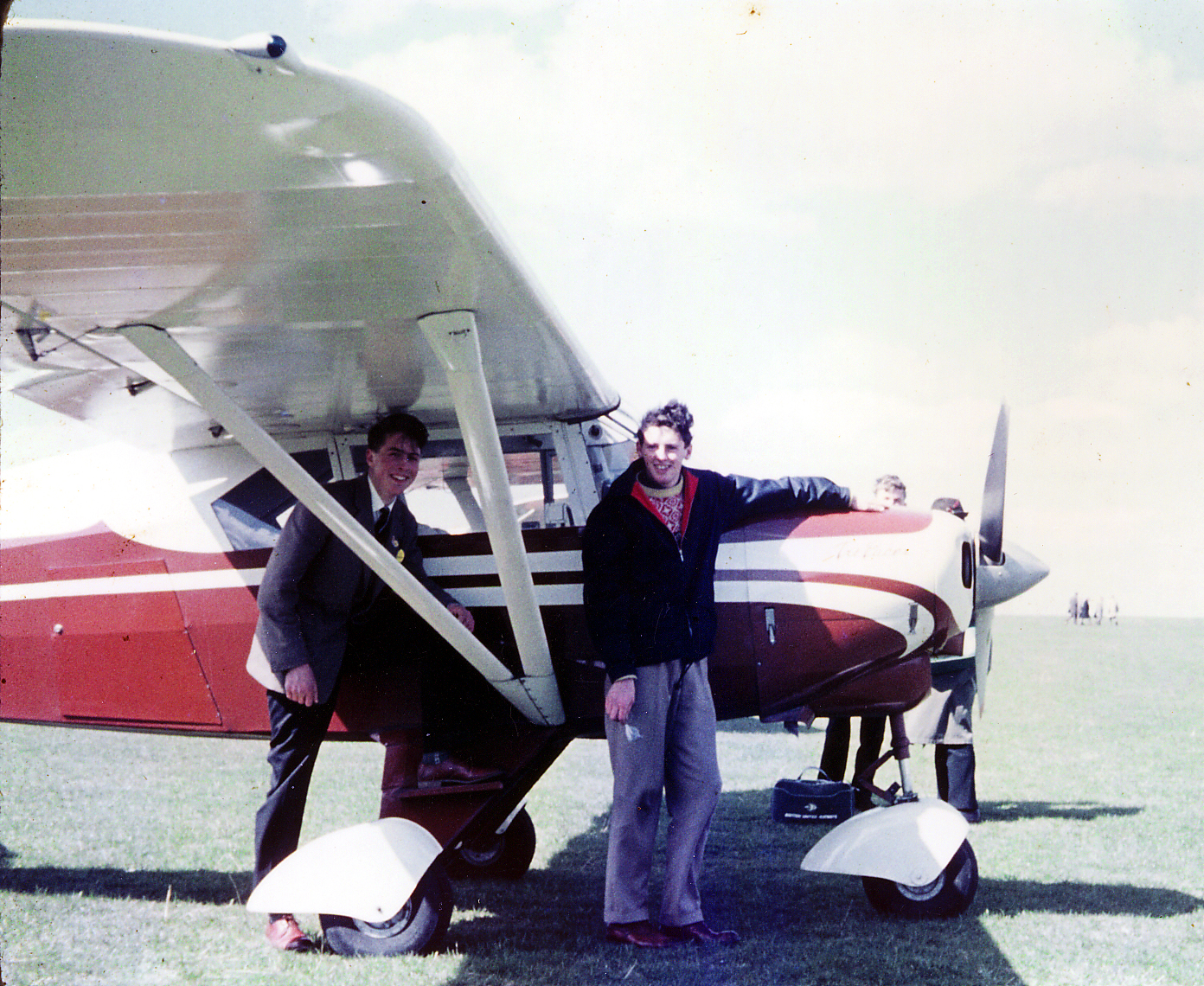 two men pose for a pograph with a small airplane