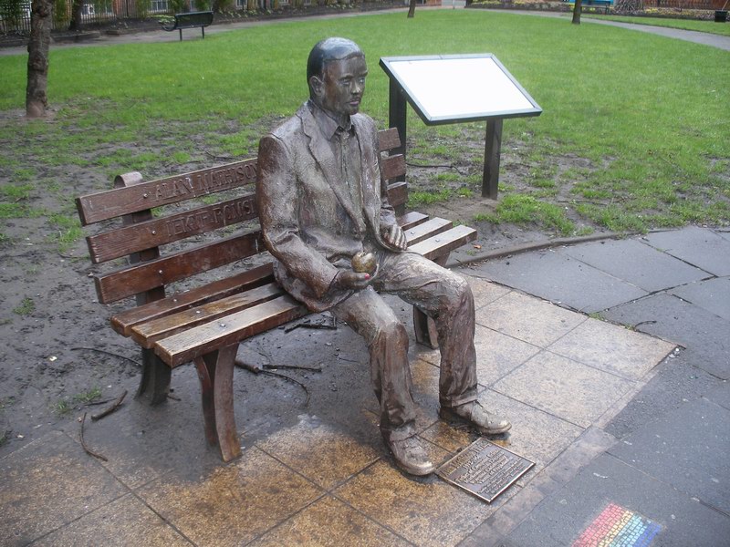 a statue sitting on top of a wooden bench