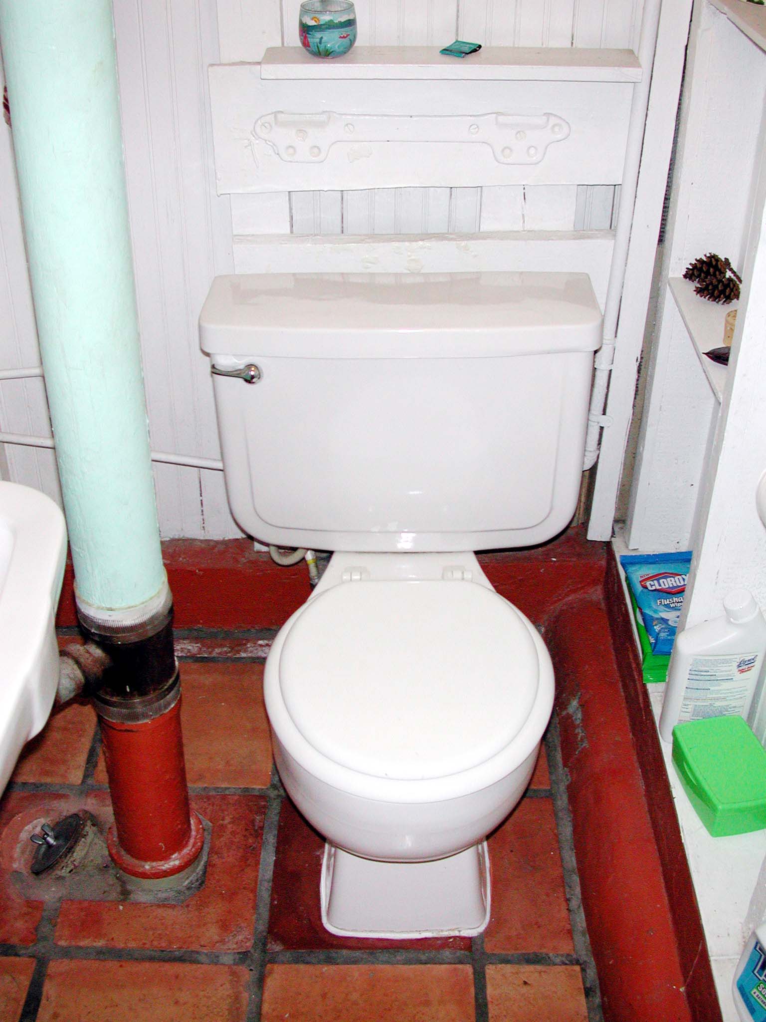 a white toilet in a bathroom next to a brick floor