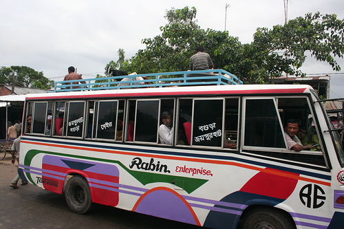 a bus with passengers on the top is traveling down a street