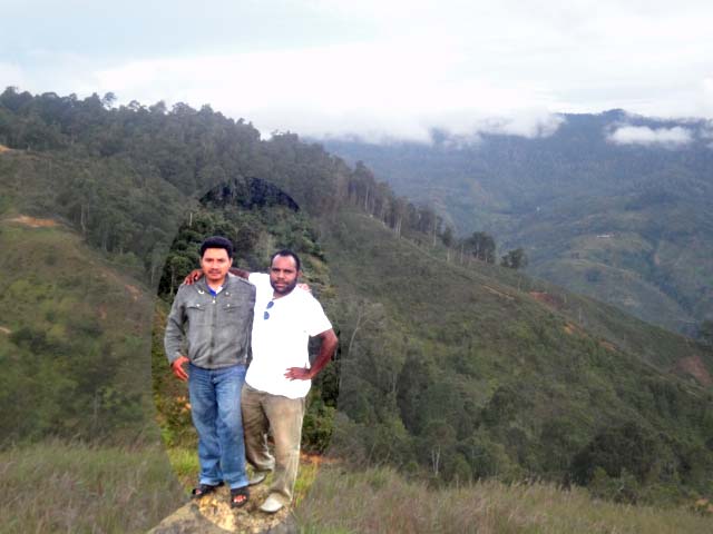 two men standing in front of trees and hills