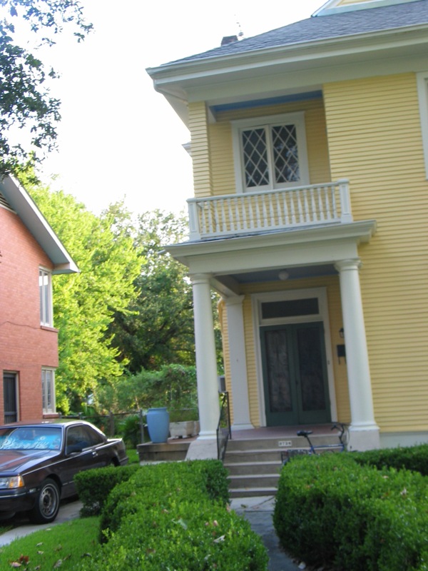 a car parked in front of a yellow two story house