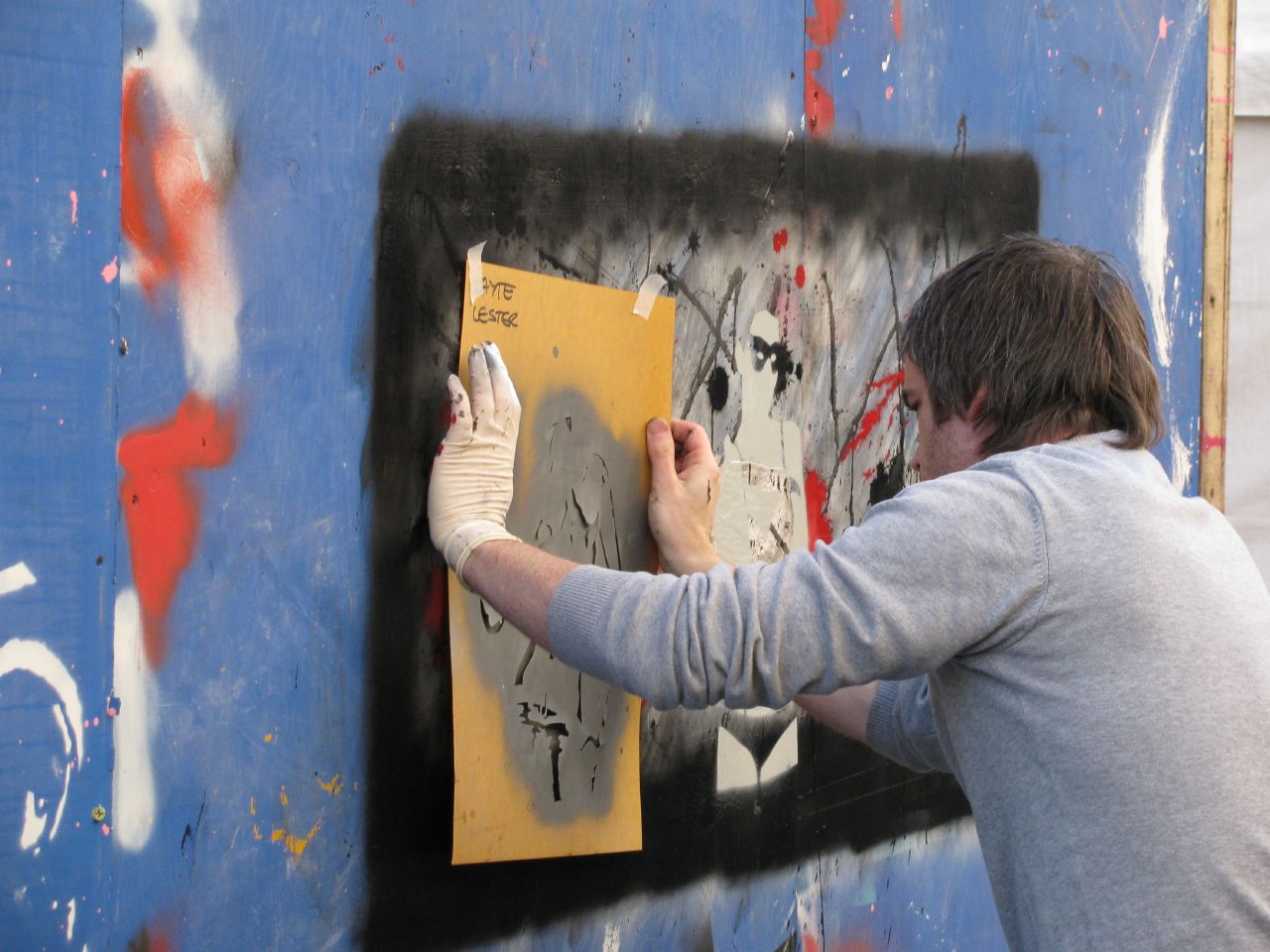 a man writing on a wall with some paint on it