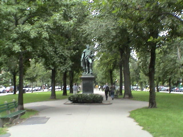 a statue stands among the trees on the side of a walkway