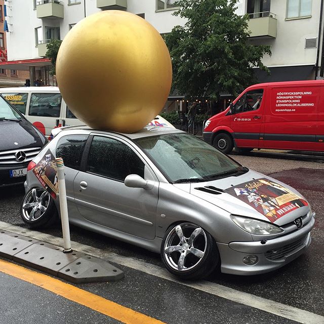 a large gold ball is sitting on the top of a silver car