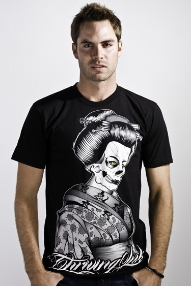 a man with his hands in his pockets, wearing a black shirt with an image of a woman's head