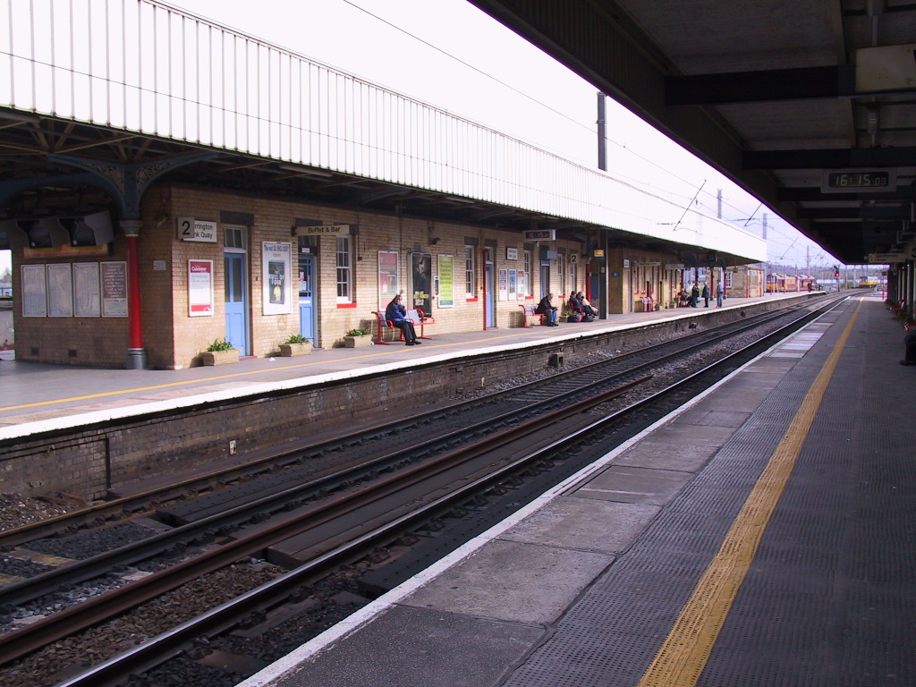 people sit at the end of a train platform as a man walks by