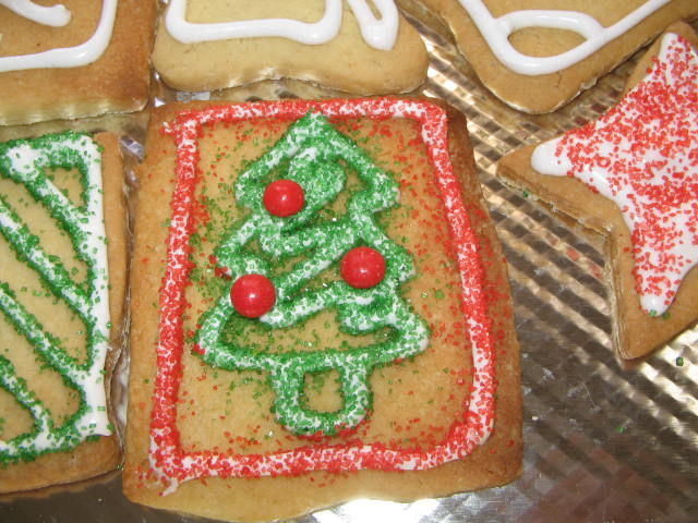 four decorated cookies in the shape of christmas trees