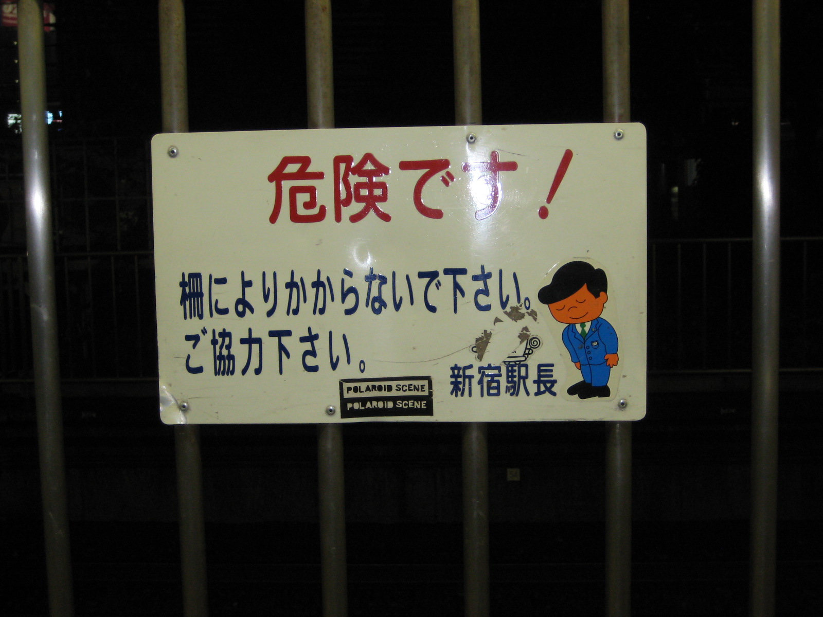 a metal gate with a sign written in the english and the asian language