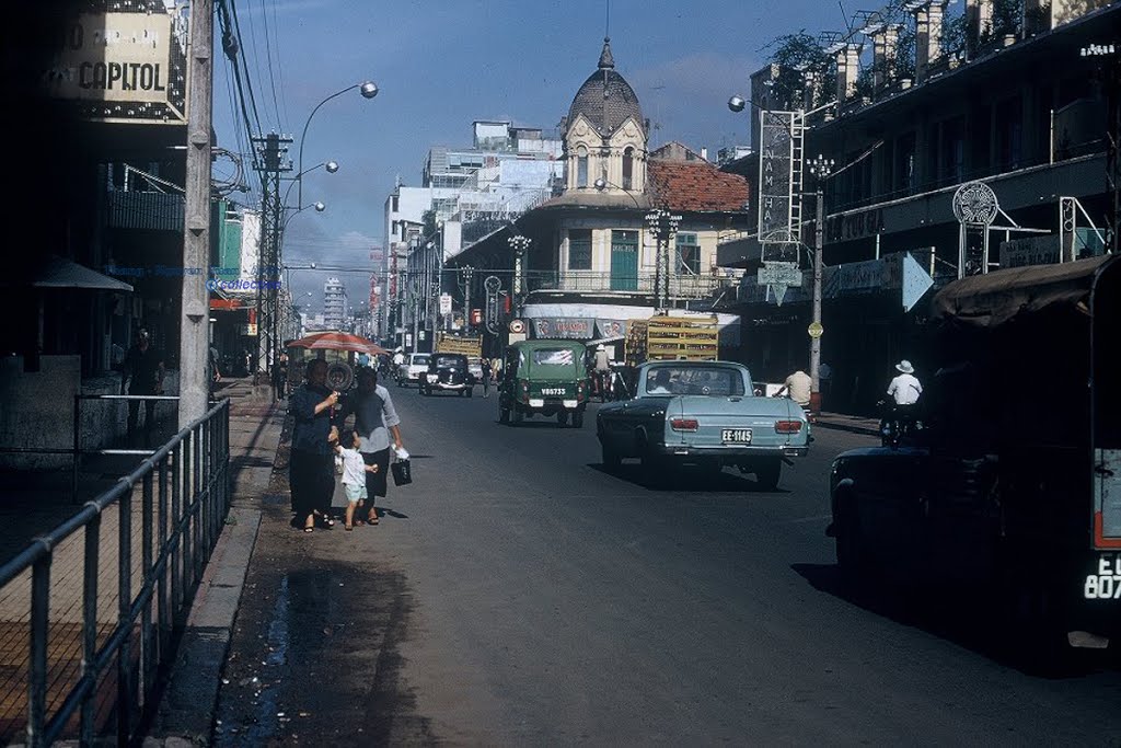 a street scene with many cars and people walking