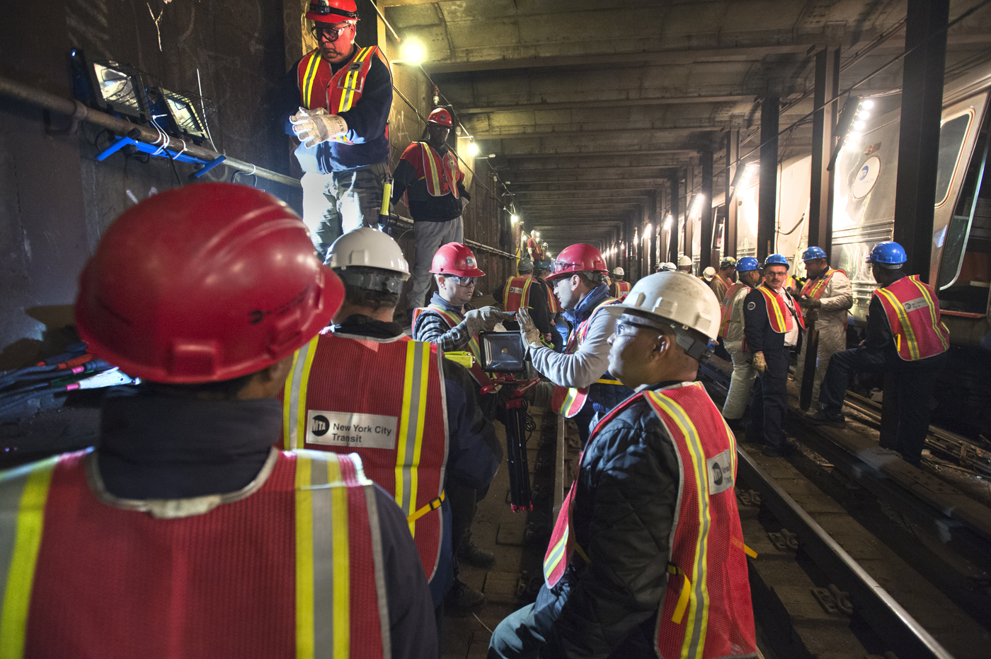 a group of people in work gear stand near train tracks