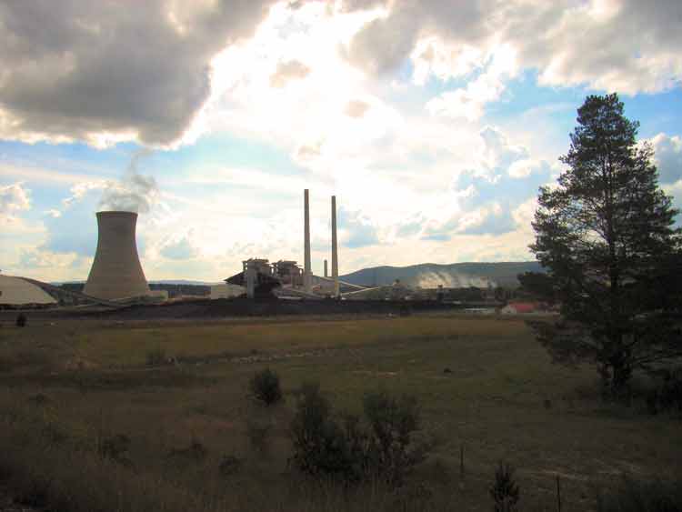 an industrial plant blowing steam at dusk with the sun coming down