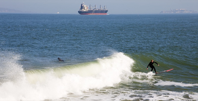 a person is surfing in the ocean with a ship