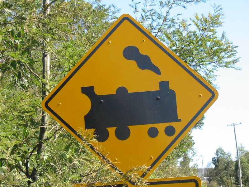 two yellow street signs showing a train crossing and an undercut