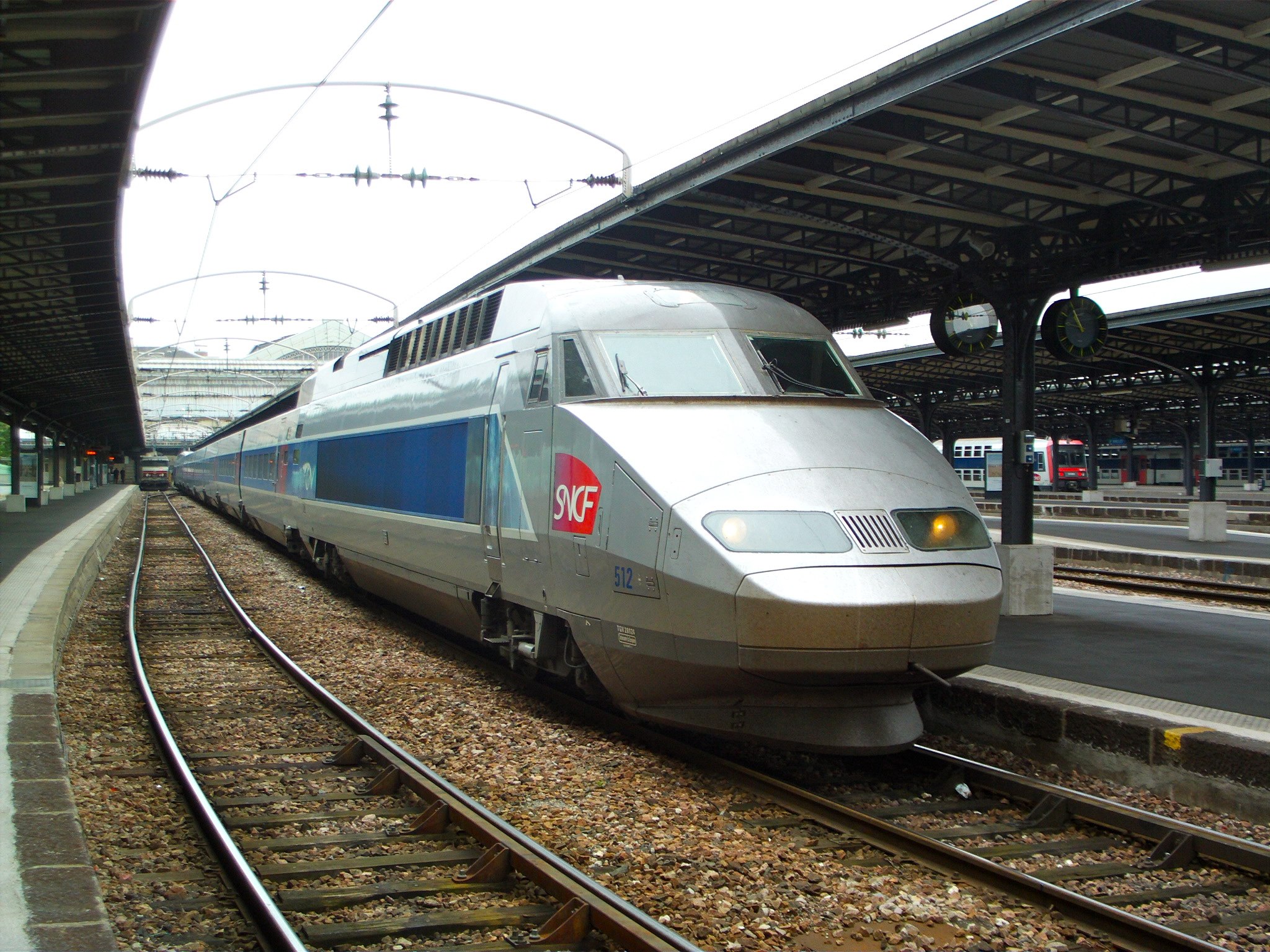 a silver and blue train traveling down tracks