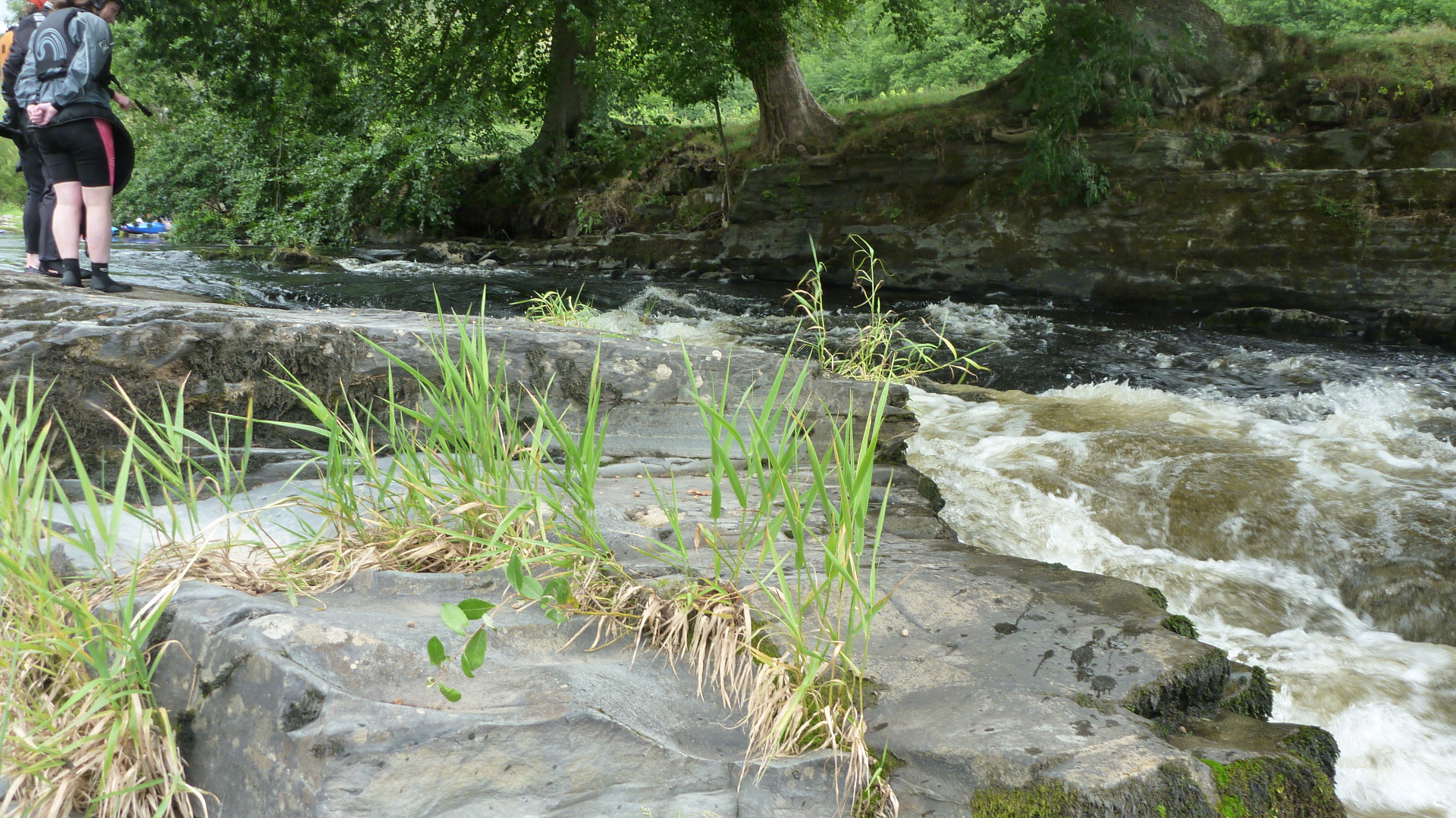 two people are standing on the rocks by a river