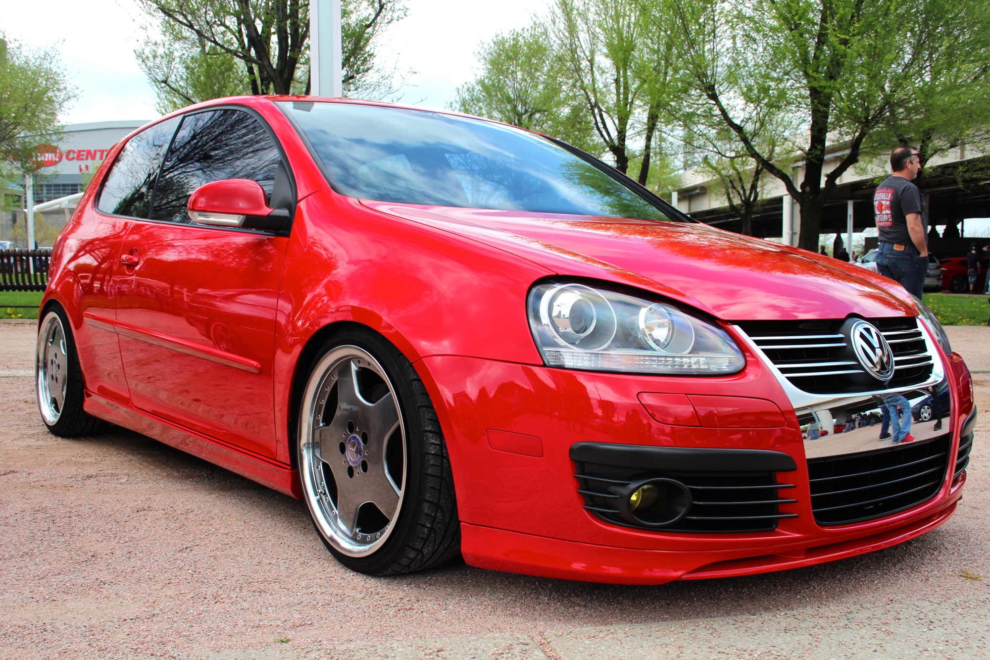 a red golf car parked on a road with another car in the background