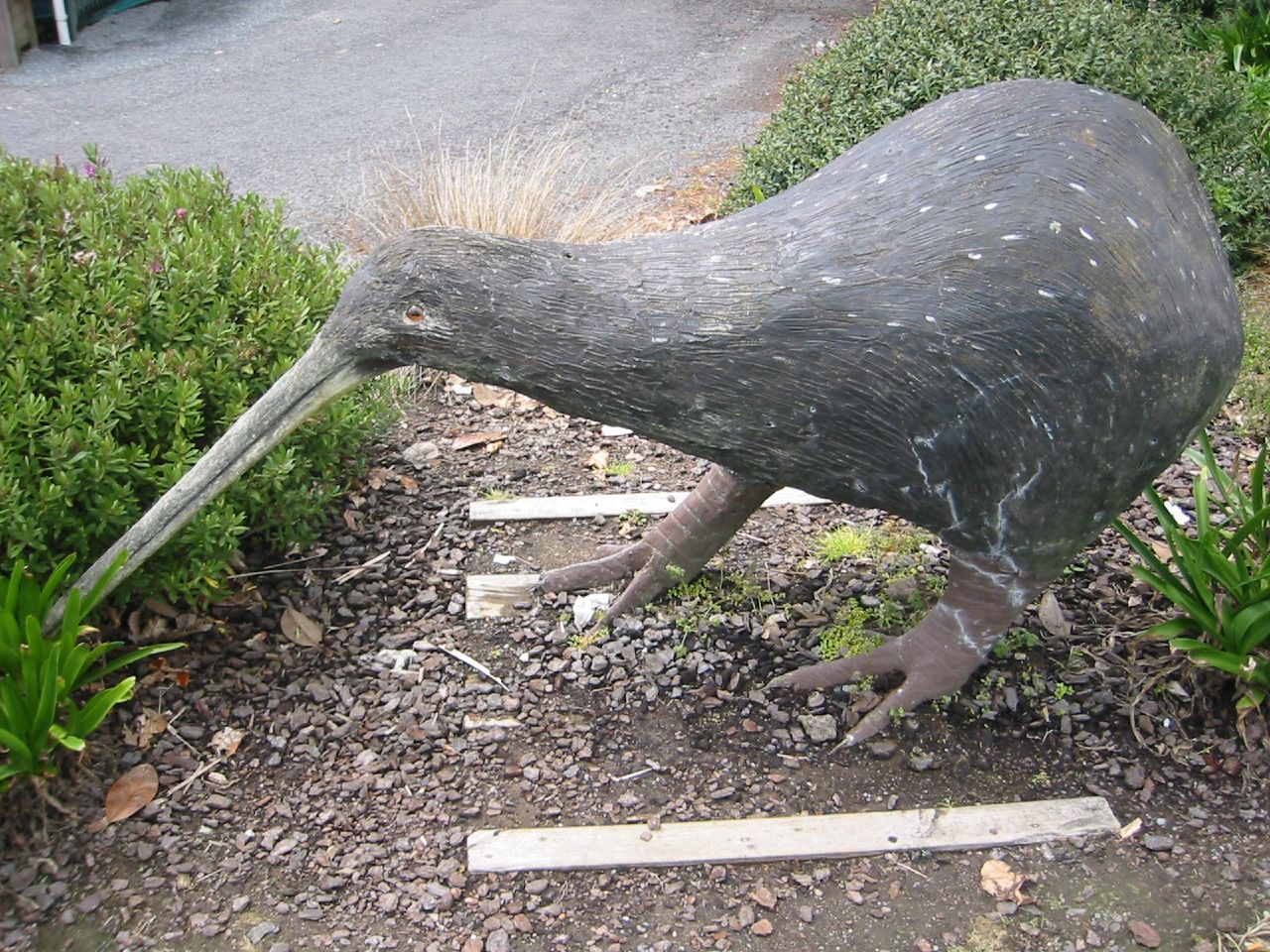 a sculpture of an ostrich eating soing in the park
