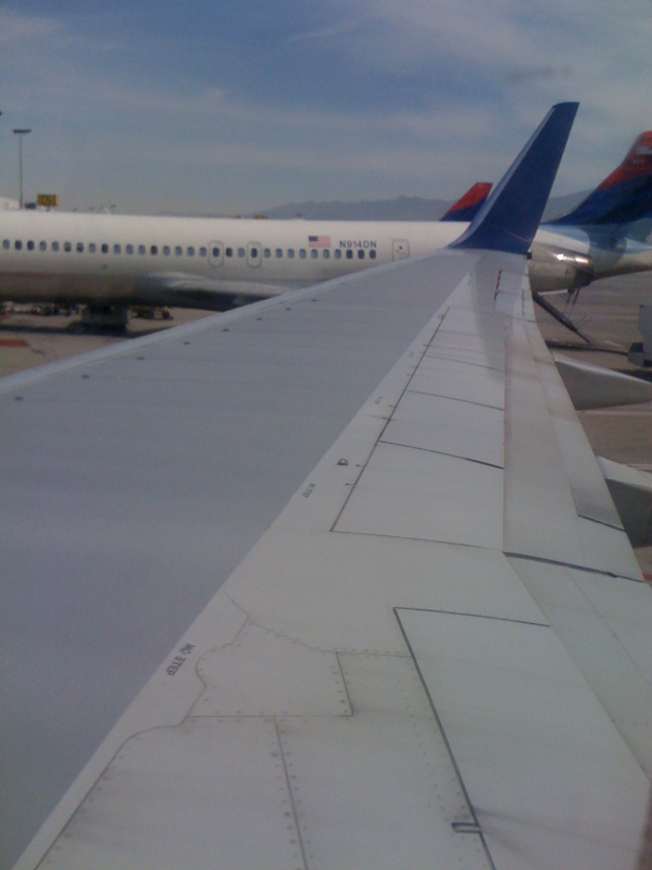 the wing of an airplane looking out over water and mountains