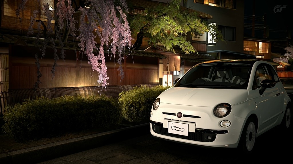 a small car parked on the street in front of some flowering trees