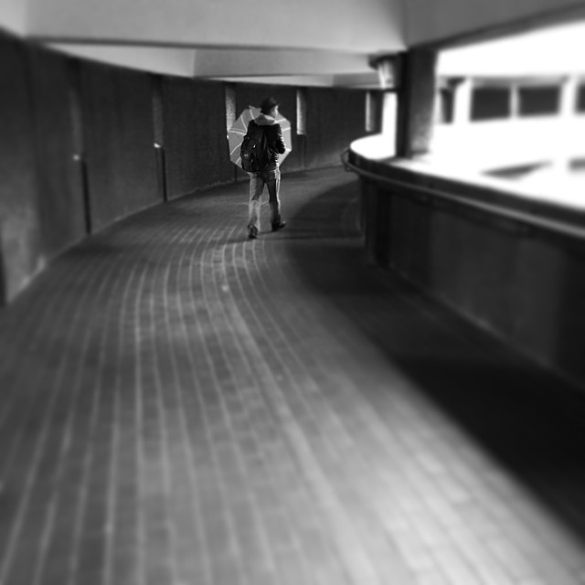 a man walks down a long hallway wearing a backpack