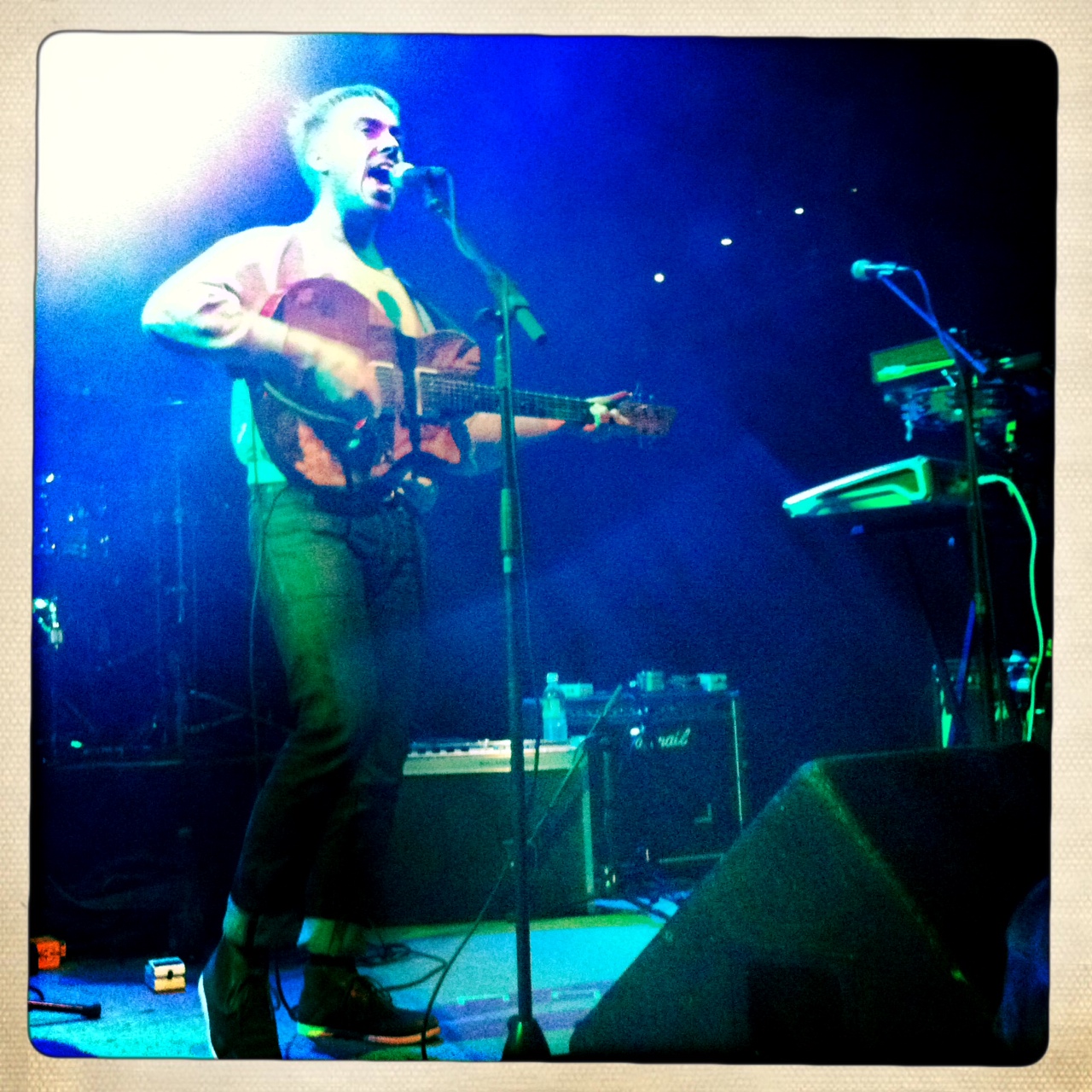 man playing guitar on stage at night with light