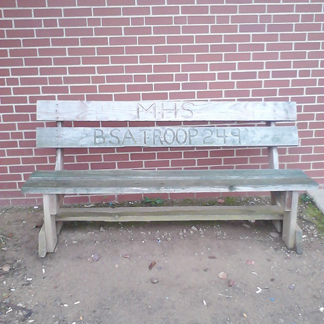 a bench on the ground by a brick wall