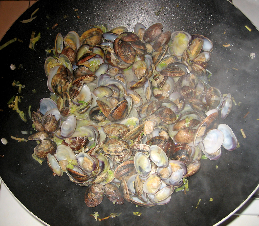 a bunch of clams frying on a pan on the stove