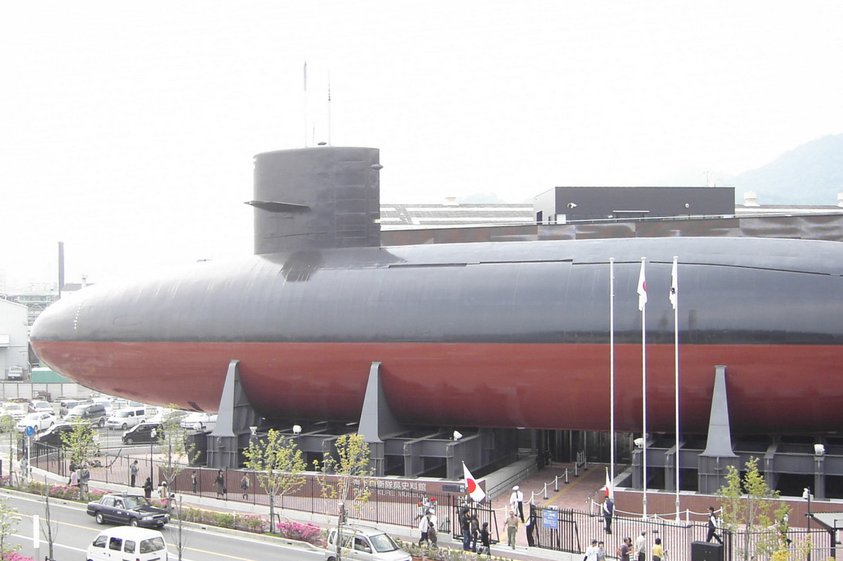 people are standing outside the large black and red submarine