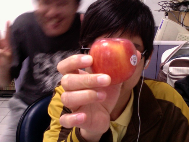 the man is wearing headphones and holding an apple