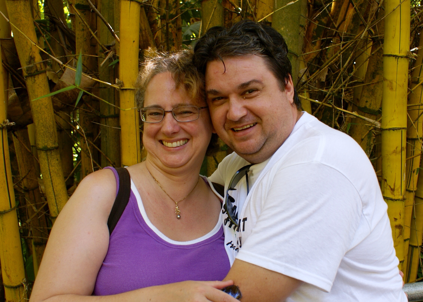 the man and woman are posing in front of bamboo fence