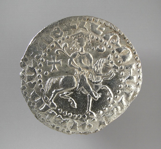 a silver coin with some white images on it