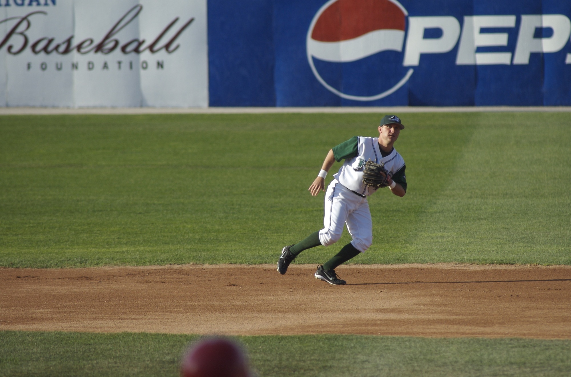 baseball pitcher on mound in white uniform preparing to throw ball