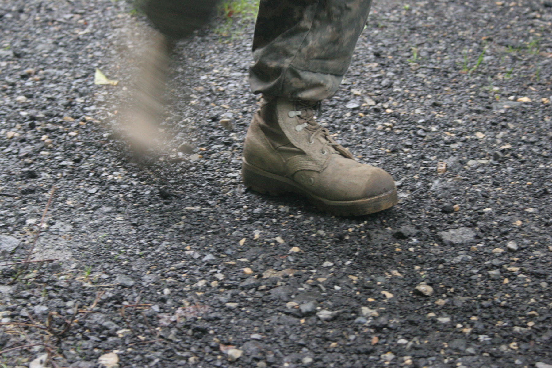 a person's foot and boots in the middle of gravel