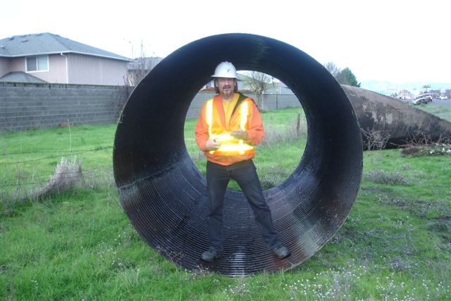 a man standing next to a large pipe