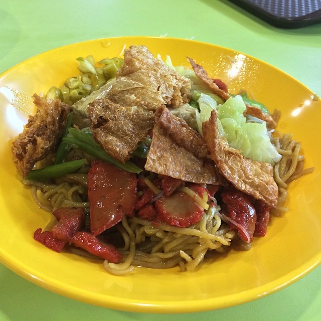 noodles with meat, vegetables and corn are served on a yellow plate