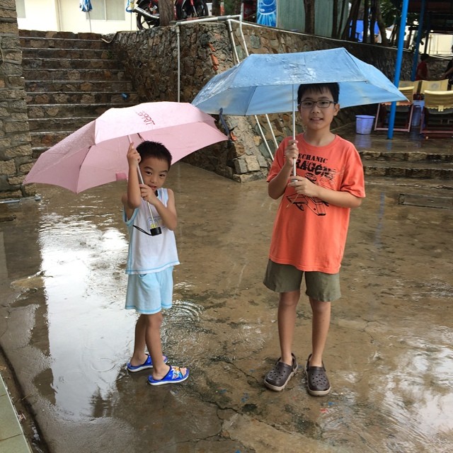 two children in the rain holding their umbrellas