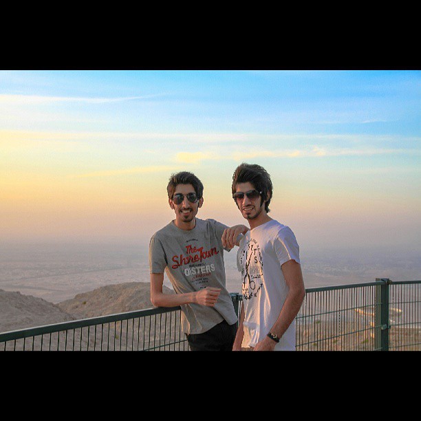 two guys posing for the camera on top of a hill