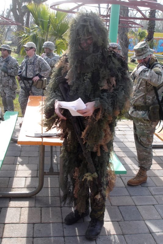 soldiers in uniform are on the pavement and around a table