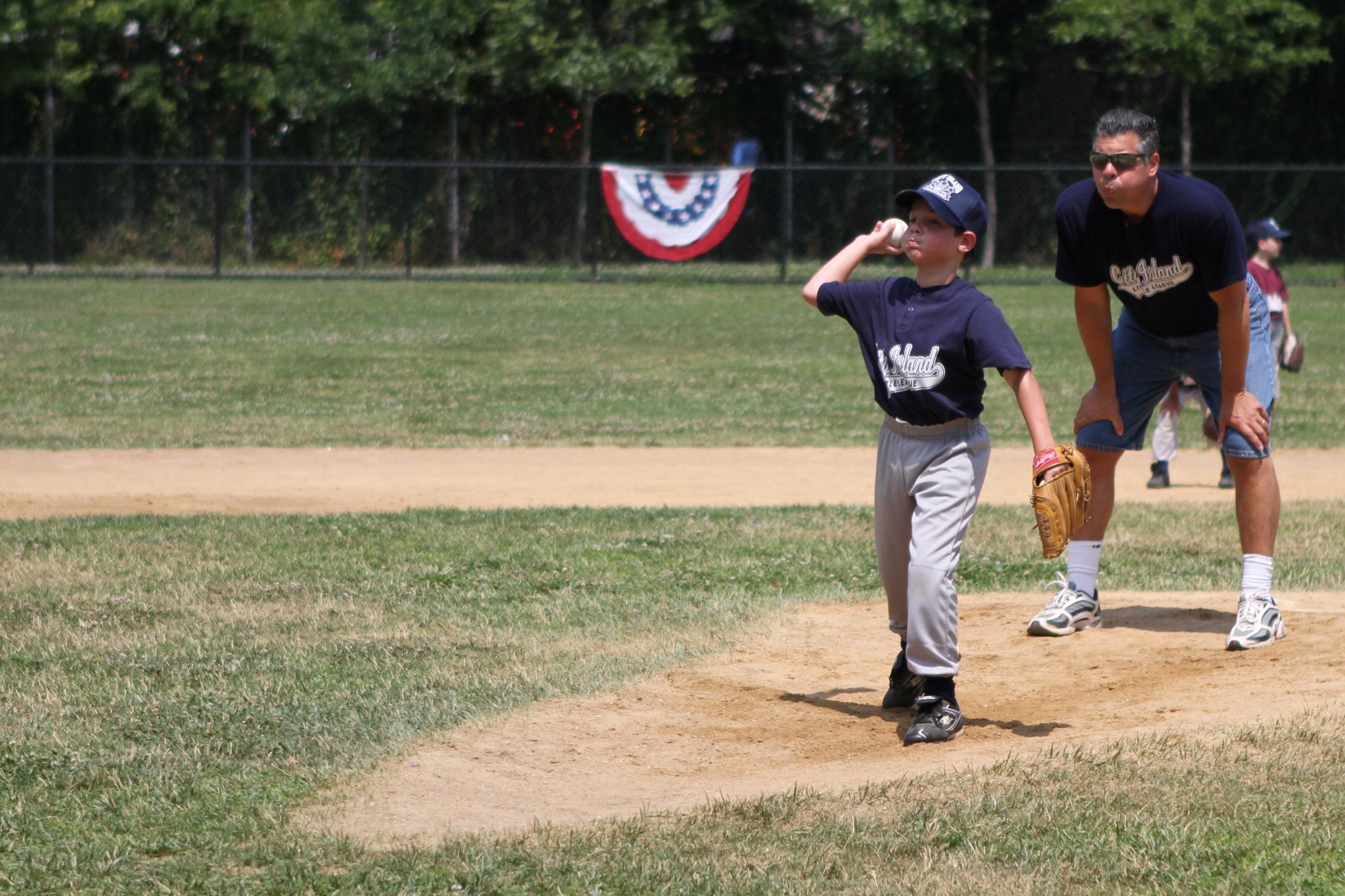 an adult watches as a boy prepares to catch a ball