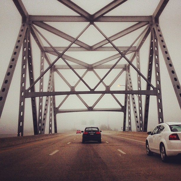 two cars are driving on a foggy road