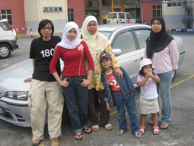 a family poses next to a car in front of a building