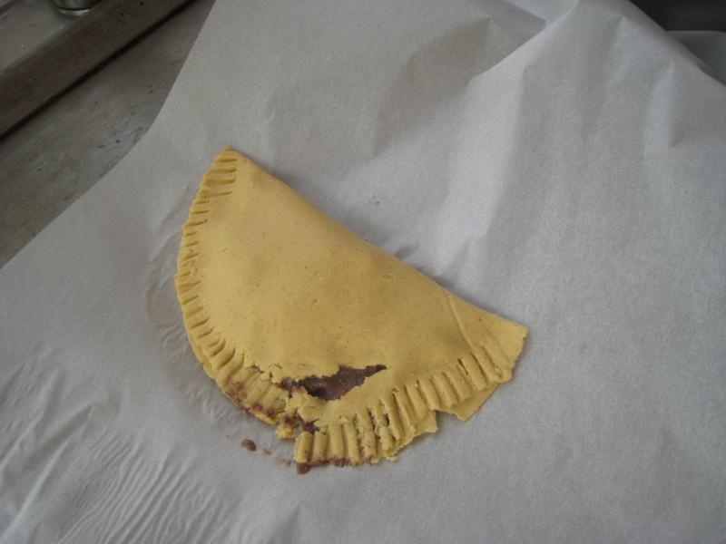 a yellow dessert with missing pastry crust on white wax paper